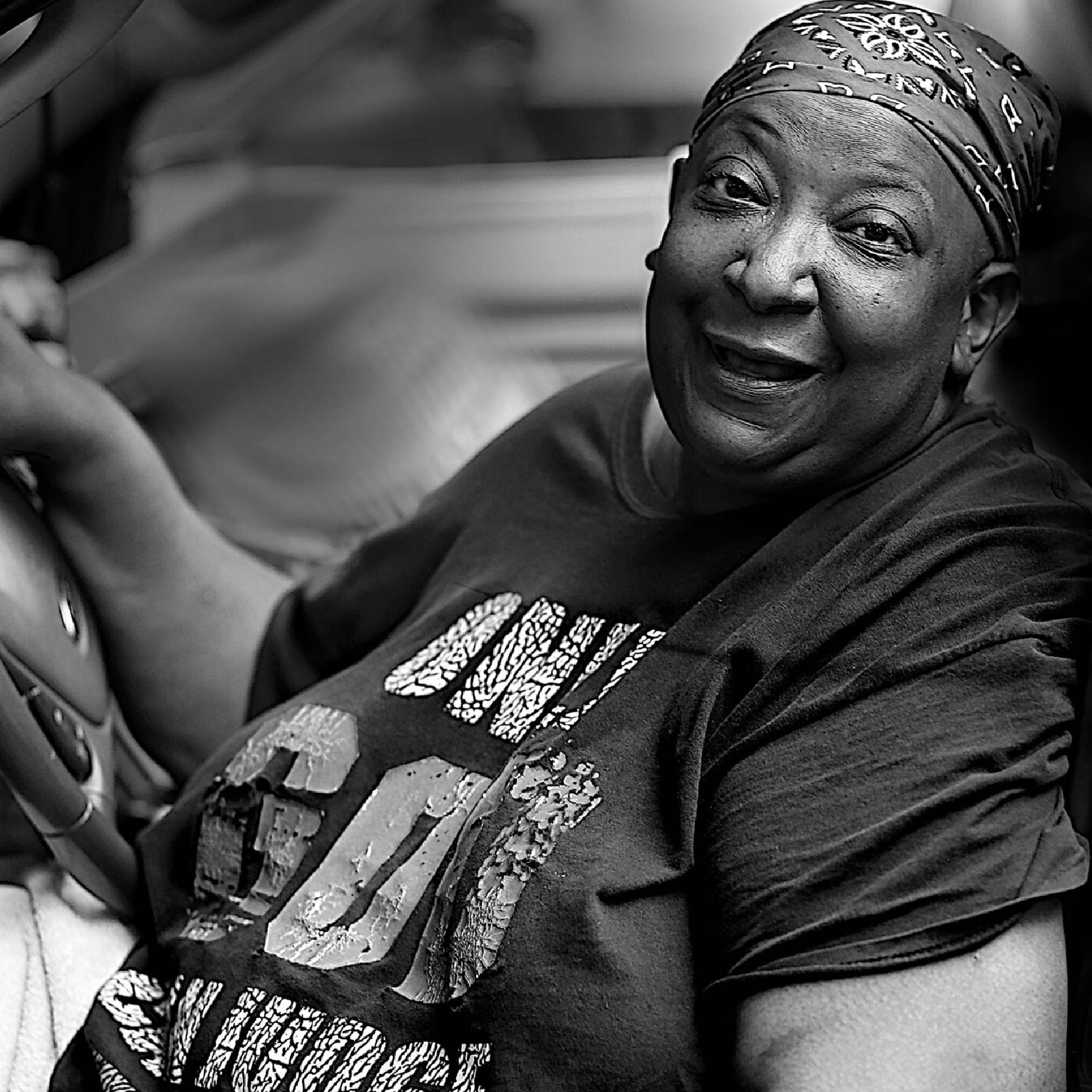An elderly African-America woman smiling from her car